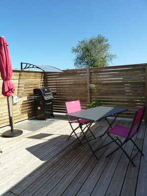 Terrasse équipée de barbecue à gaz, table, chaises