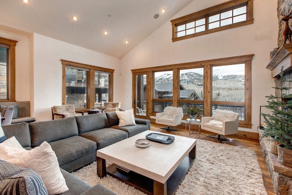 Living Room with plush sectional sofa, 65" Samsung smart tv, gas-assist fireplace, two separate seating areas, and private balcony access