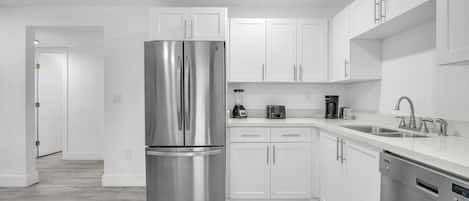 A sleek, clutter-free kitchen with all the necessary amenities, including a spacious refrigerator, dishwasher, and essential cooking tools.