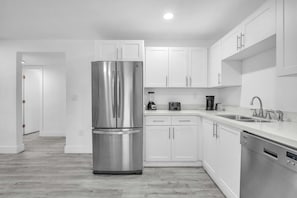 A sleek, clutter-free kitchen with all the necessary amenities, including a spacious refrigerator, dishwasher, and essential cooking tools.