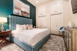 Side 2: Spacious guest bedroom with a king bed, ensuite bath, and designer built-in closets. Includes nightstands, lamp, alarm clock, white noise machine, and a 50'' Samsung Smart 4K TV with streaming and DIRECTV Entertainment.