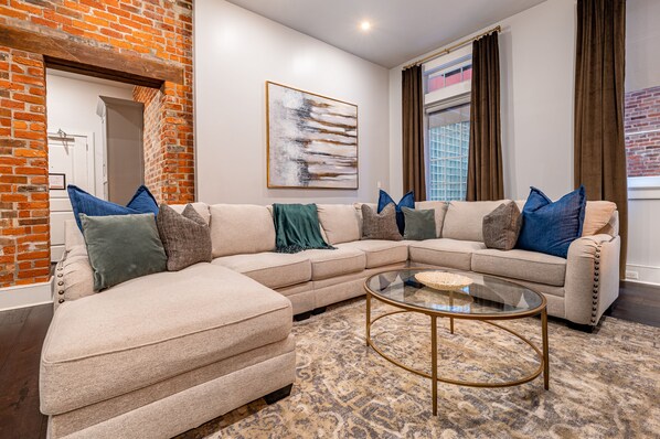 Side 1: Open-concept living and dining area with plenty of seating. Enjoy a 55" Samsung Smart 4K TV with streaming and DIRECTV Entertainment. Relax on the extra-large sectional after a fun-filled day in NOLA!