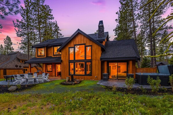 This architectural masterpiece glows at dusk with expansive windows and luxury lodge presence