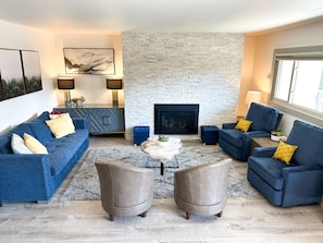 Living room with gas fireplace, blue sofa on the left is a queen pullout bed
