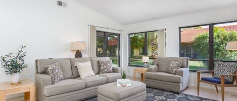 Vaulted ceilings in the living room with a quality-made sofa, chair and ottoman