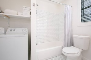 Clean bright white bathroom with tub/shower combo and private full size laundry 