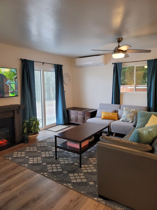 View of the living room with electric fireplace and 55 inch rotating T V.