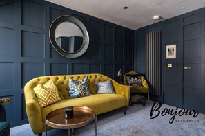 Stylish living room with comfortable sofa, arm chair and decorative mirror