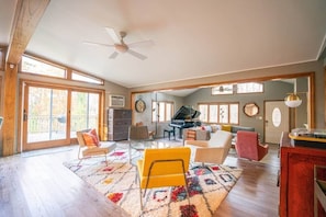 Open concept living room area with sectional, smart TV and grand piano. 