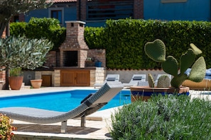 Atemberaubender Poolbereich im Garten mit Loungemöbeln, Sonnenliegen und Grillmöglichkeiten