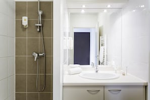 The modern and full bathroom features a shower and a towel dryer