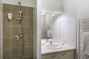 The modern and full bathroom features a shower and a towel dryer