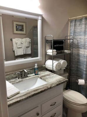 Bathroom with tub/shower and plush linens.