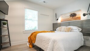 This cozy bedroom has a queen bed, wall hooks for hanging and underbed storage