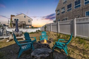 Back deck with outdoor couch set-up, hammock, fire pit with seating and fenced-in backyard
