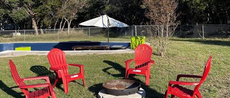 Fire pit in the backyard, next to the in-ground deck and porch