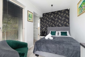 The stylish bedroom includes a comfortable double bed and an armchair.