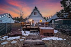 Back deck, lounger, jacuzzi and fenced yard with lights on the deck (winter)