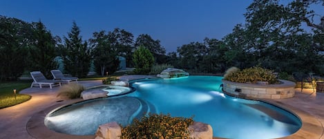 The area is illuminated by the pool lights at night