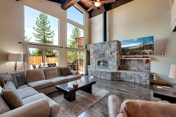 A cozy living space with a stone fireplace and floor-to-ceiling windows.
