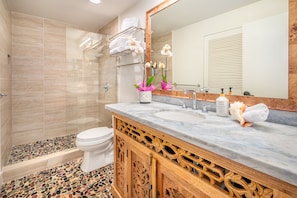New luxury bathroom with stone counter, huge shower head & stone pebble floors.