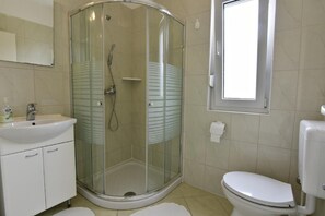 Bathroom 1 equipped with shower, sink with cabinet and mirror, toilet.