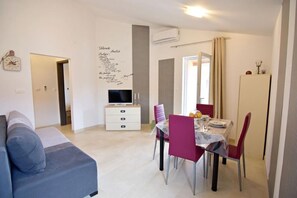 The living area with flat screen satellite TV, dining table with chairs