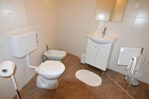 La salle de bain avec douche, WC, bidet, lavabo avec miroir