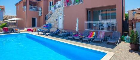 The front of the house, the pool area with sun loungers for shared use