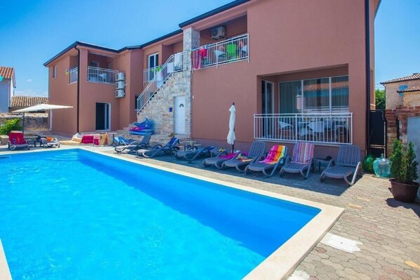 The front of the house, the pool area with sun loungers for shared use