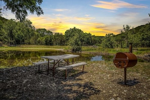 A charcoal grill and picnic table right at the pond's edge make for a wonderful setting for a BBQ feast!