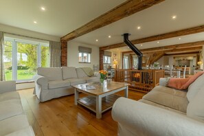 The Big Barn, Snettisham: A view across the open-plan living area with double-sided wood burning stove