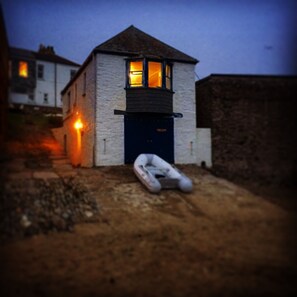 Watch House at night with guest's boat on slipway