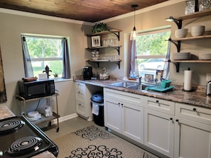 This kitchen is stocked with pots, pans, mixing bowls, cutlery, and dishes.