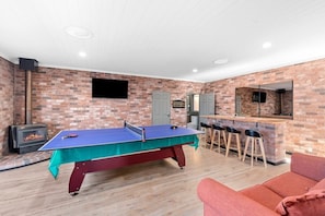 Downstairs games room with plush seating, bar with bar fridge, wood fireplace and table tennis table (bats and balls provided)