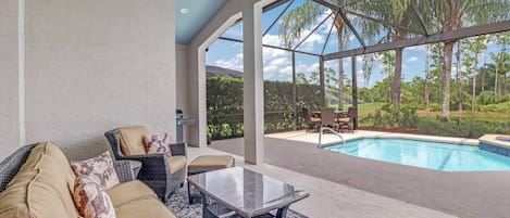 The fully screened outdoor space includes a lounge area, grill, dining table, and heated pool with spa.