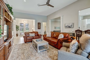 The open concept living space includes leather sofa and loveseat, and a comfortable recliner.