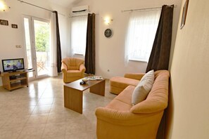 The living area with sofa bed, armchair, coffee table, satellite TV.
