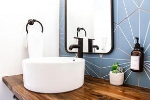 Upstairs bathroom with double vanities and Public Goods toiletries.