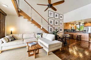 Living Area with Loft Staircase, Cream Colored Sectional and Views of the Kitchen