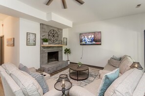 Step down into the inviting lower level designed for relaxation and entertainment. This spacious living area features comfortable sofas that invite you to unwind, a mounted flat screen TV perfect for movie nights, and a sleek electric fireplace that adds warmth and ambiance.