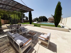 Salon de jardin sur la terrasse avec vue sur la piscine et le Pool House