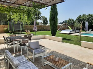 Salon de jardin et table à manger sous la grande pergola suspendue ombragée