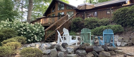 Lakeside view of house, complete with large deck and built in fire pit