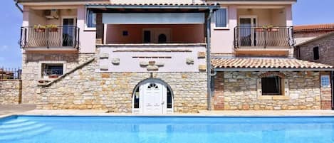 The front side of the house where the apartment is located and the splendid swimming pool