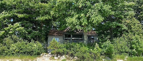 View of house and sandy beach from the water, summer 2023. 