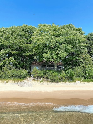 View of house and sandy beach from the water, summer 2023. 