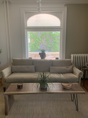 View from TV wall of the couch and the window which looks onto the side porch.