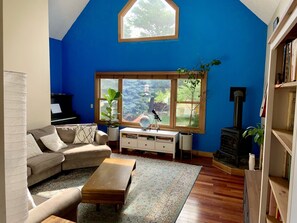 Living room looking out at backyard, with 55" TV, upright piano, electric stove