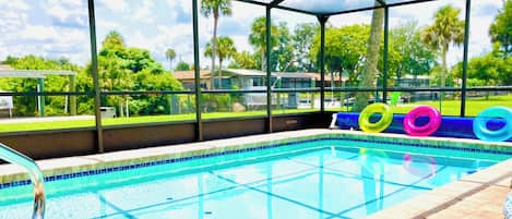 Pool area overlooking large backyard, canal, & dock area.